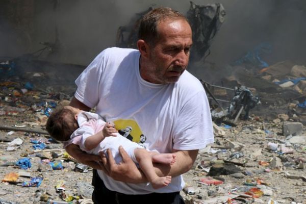 Homem segura beb que sobreviveu a bombardeio com barris explosivos em Aleppo nesta quarta-feira (3)