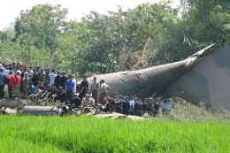 Equipes de resgate se renem em torno da fuselagem do avio indonsio que caiu sobre arrozal depois de atingir casas