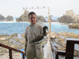 Marinheiro Luiz Eduardo Cabral segura exemplar de atob, que recebeu anilha de pesquisadores para monitoramento ambiental
