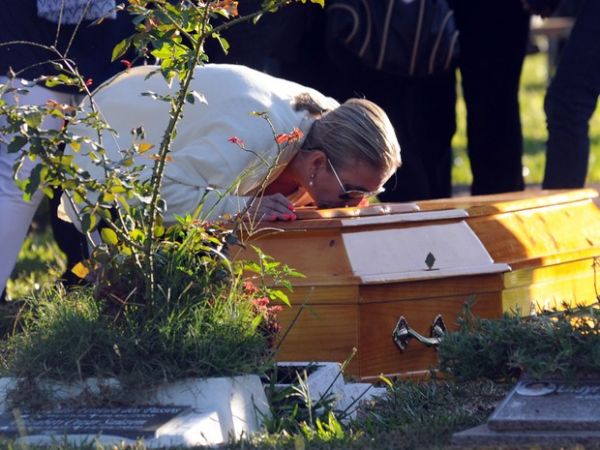 Livia Oliveira, me de Heitor, se ajoelha para beijar o caixo do filho durante enterro