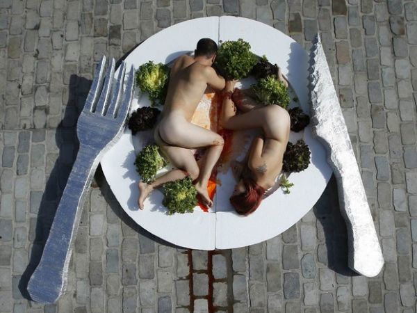 Ativistas defendem dieta vegetariana deitando sem roupa em prato gigante