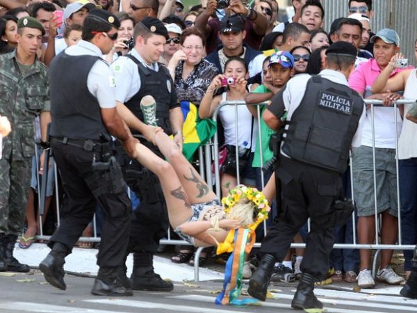 Ativista do grupo feminista Femen tira a blusa e exibe cartaz de protesto ao invadir a pista onde acontecem os desfiles de 7 de Setembro na Esplanada dos Ministrios, em Braslia. Duas ativistas foram presas.