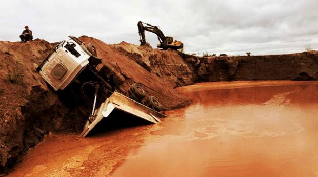 Caminho caamba cai em buraco de garimpo aps deslizar em barranco